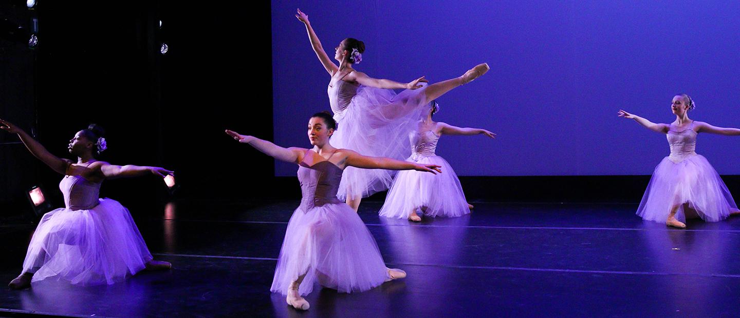 一个舞者伸展着她的腿和手臂，背景是四个舞者